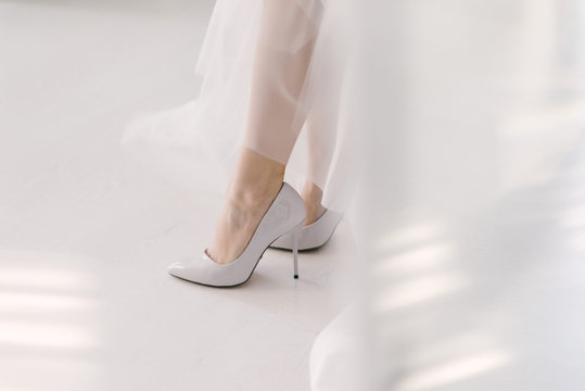 The legs of the bride in a wedding dress in shoes