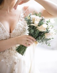 Obraz na płótnie Canvas Bride in a wedding dress holding a wedding bouquet in her hands close-up