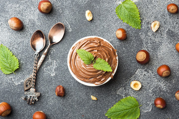 Nougat nut chocolate in a plate on a dark concrete background with hazelnut nuts. Concept of...