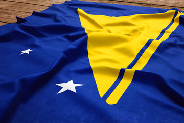 Flag of Tokelau on a wooden desk background. Silk flag top view.