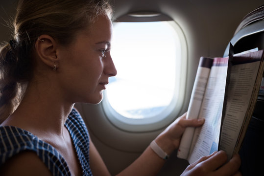 Caucasian woman reading a magazine during her flight