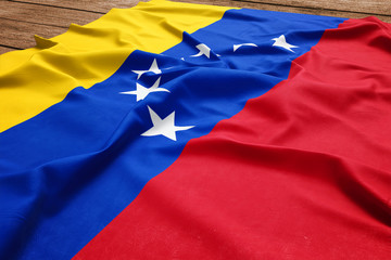 Flag of Venezuela on a wooden desk background. Silk Venezuelan flag top view.