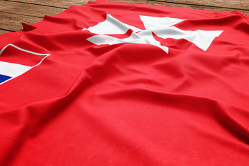 Flag of Wallis And Futuna on a wooden desk background. Silk flag top view.
