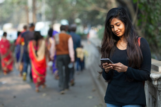 Young girl browsing smartphone in a street of urban area