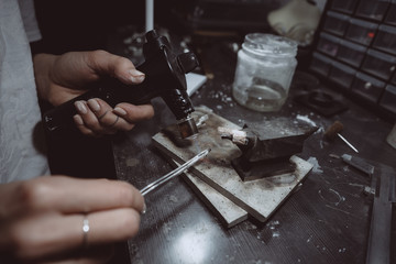 In the workshop, a woman jeweler is busy soldering jewelry