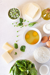Ingredients for making tart, quiche, pie or cake - flour, eggs, milk, olive oil, spinach, green pea, cheese and butter. Food background. Copy space.