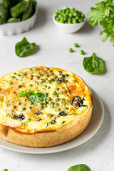 Spinach and green pea quiche, tart or pie with fresh ingredients for baking. Light grey background, copy space. 