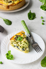 Spinach and green pea quiche, tart or pie with fresh ingredients for baking. Light grey background, copy space. 