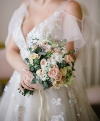 Bride in a wedding dress holding a wedding bouquet in her hands close-up