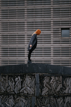 woman playing/dancing in front of a functional architecture building
