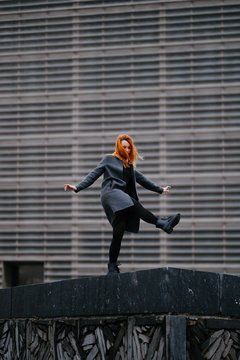 woman playing/dancing in front of a functional architecture building