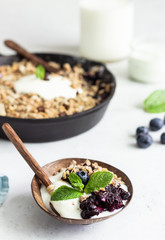 Oatmeal crumble in cast iron pan with fresh blueberry and natural yogurt. Healthy food concept. 