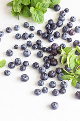 Fresh blueberries and mint leaves on light grey stone background. Organic food for healthy lifestyle. 