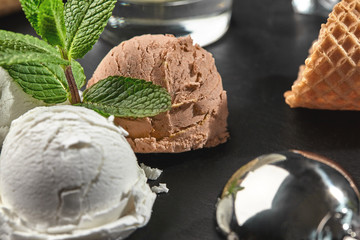Gourmet creamy and chocolate ice cream served on a stone slate over a black background.
