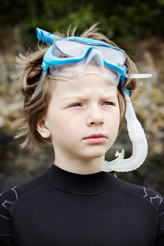 A young boy prepares for a swim with goggles and snorkel