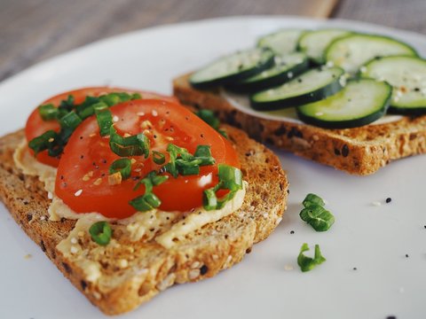 A healthy, hearty vegetable toast lunch sandwich with tomatoes, cucumbers and chives