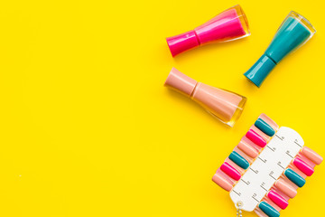 cosmetics for manicure with nail polish and palette for spring design in nail bar yellow background top view copyspace