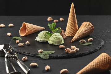 Gourmet chocolate and pistachio ice cream served on a stone slate over a black background.