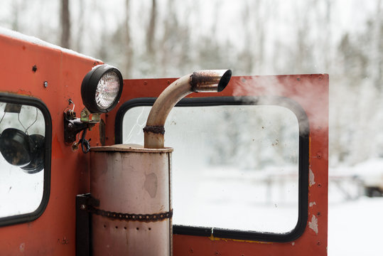 Dirty pollution exhaust spews from muffler of old vintage snow grooming machine