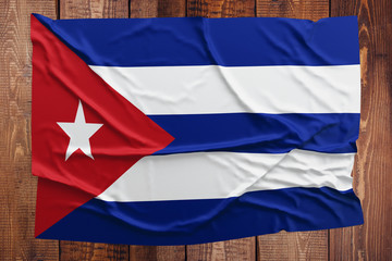 Flag of Cuba on a wooden table background. Wrinkled Cuban flag top view.