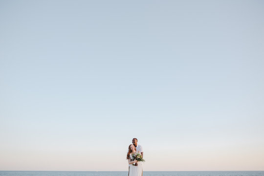 Affectionate, happy just-married couple together at sunset on th