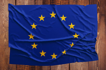 Flag of European Union on a wooden table background. Wrinkled flag top view.