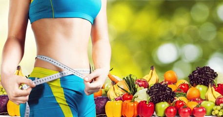 Young woman with measuring tape on healthy food background