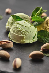 Gourmet pistachio ice cream served on a stone slate over a black background.