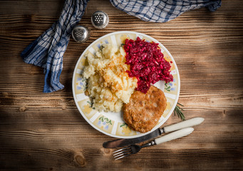 Pork cutlet with minced meat served with boiled potatoes and beetroot.