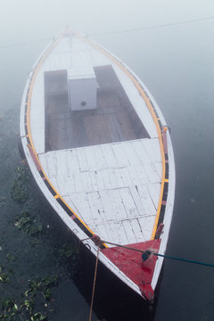 Pink boats in the water of the Ganges river during a densely foggy morning