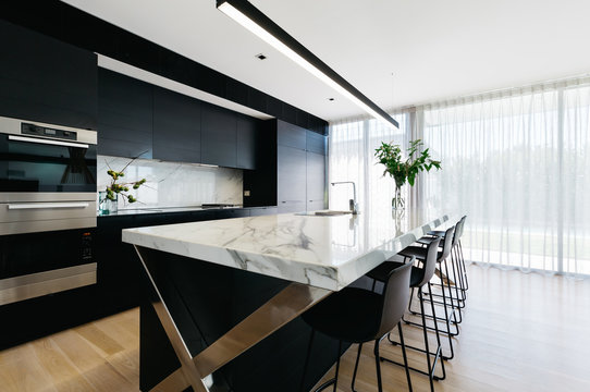 Luxury open plan black kitchen with calcutta marble benchtop