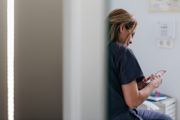 Doctor woman having a break and checking her mobile phone