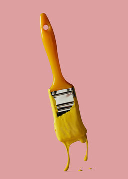 Yellow brush with drops of yellow paint isolated on a pink background