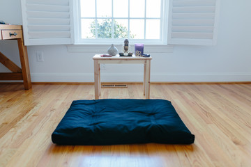 View of a meditation cushion and shrine in front of a window