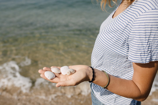 Blonde woman holding sea shells in her hand