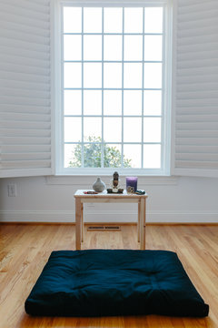 View of a meditation cushion and shrine in front of a window