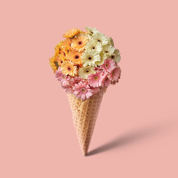 Waffle cone with bouquet of beautiful flowers on pink background