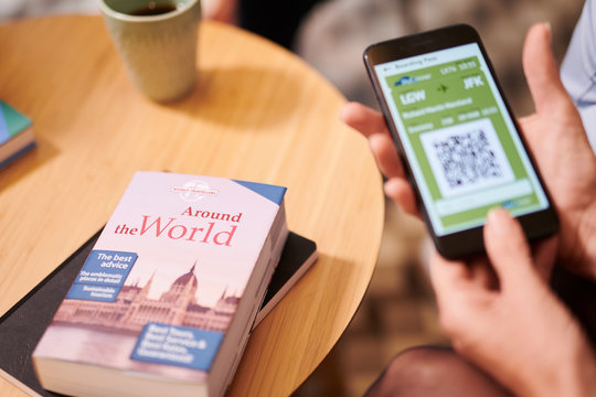 Touristic guide book on wooden table beside cell phone with check QR code