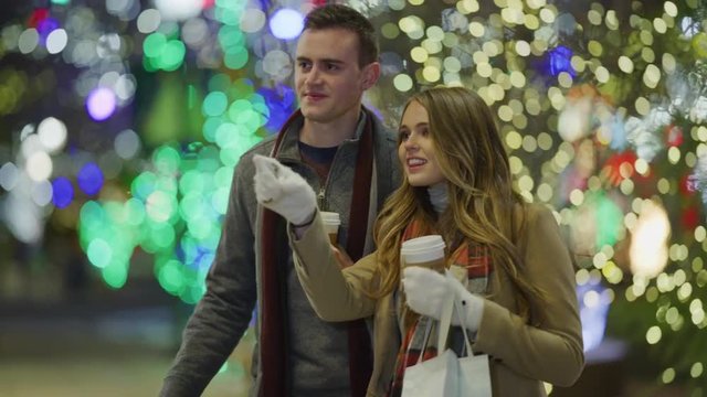 Couple walking outdoors during Christmas carrying shopping bags then window shopping / Provo, Utah, United States