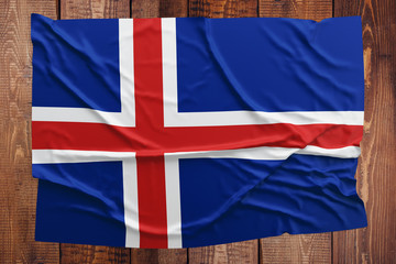 Flag of Iceland on a wooden table background. Wrinkled Icelander flag top view.