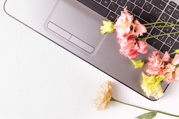 White table with laptop and flowers. Freelancer workspace.