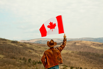 A man in a cowboy hat take canadian flag
