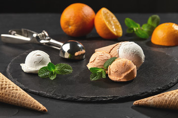 Fototapeta na wymiar Close-up shot of a creamy and orange ice cream served on a dark slate, black background.