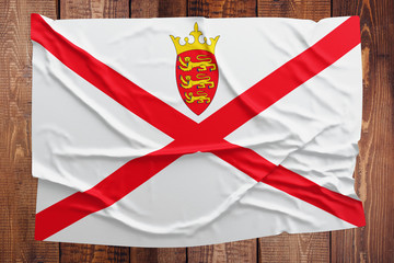 Flag of Jersey on a wooden table background. Wrinkled flag top view.