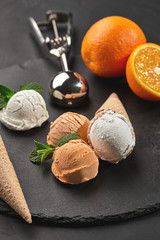 Close-up shot of a creamy and orange ice cream served on a dark slate, black background.