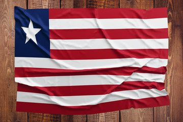 Flag of Liberia on a wooden table background. Wrinkled Liberian flag top view.