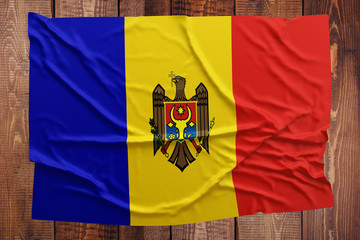 Fototapeta premium Flag of Moldova on a wooden table background. Wrinkled Moldovan flag top view.