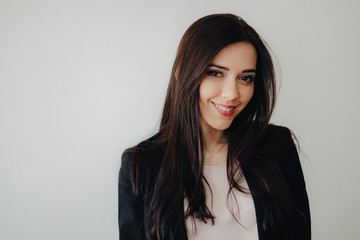 Fototapeta premium Young attractive emotional girl in business-style clothes on a plain white background in an office or audience