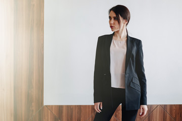 Young attractive emotional girl in business-style clothes on a plain white background in an office or audience