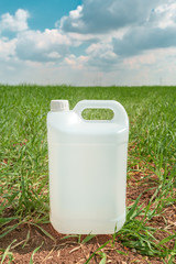 Blank pesticide jug container mock up in wheatgrass field